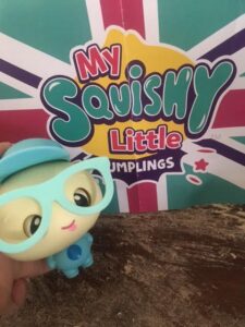 dot dumpling in front of the flag logo with his glasses and hat on
